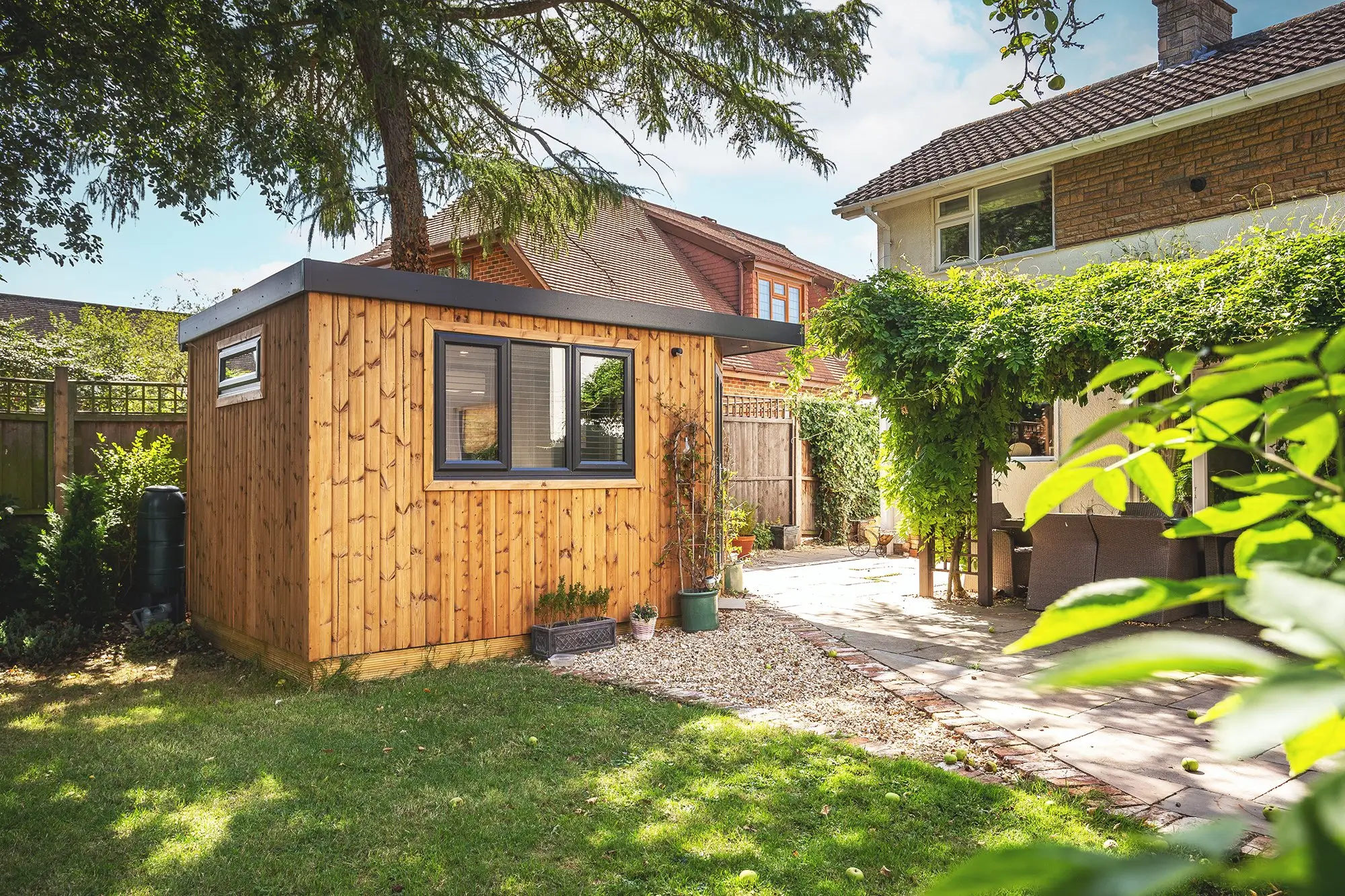 Cabin Master Redwood Garden Shoffice Pod in Garden with Patio and Foliage 