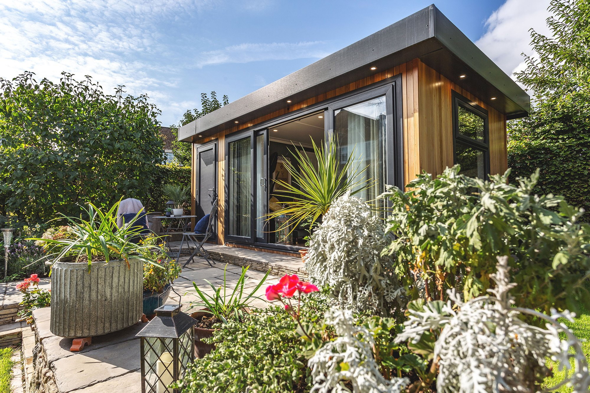 Large Garden Room in patio area surrounded by foliage and with a table and chairs in front