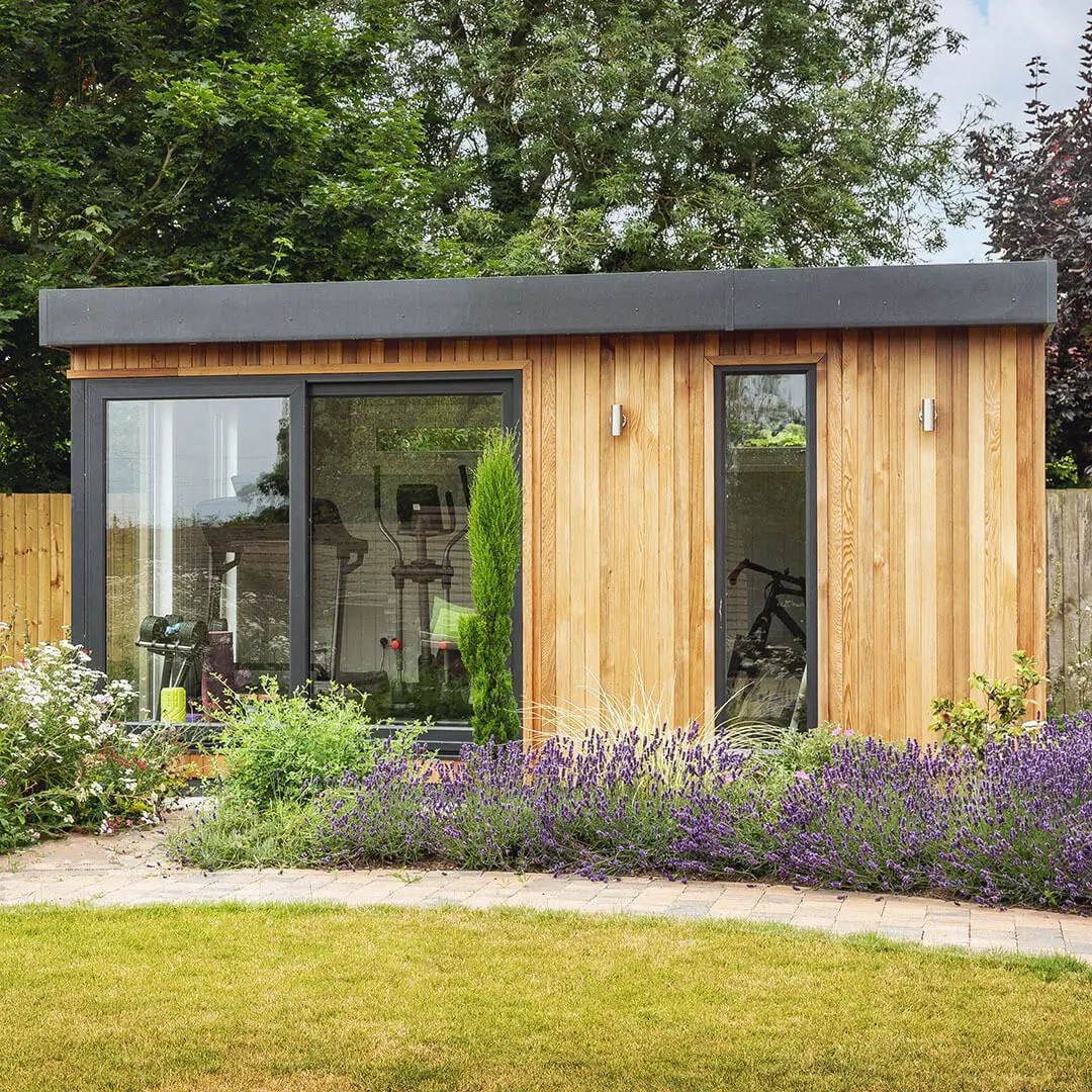Luxury bespoke garden gym cabin in cedar with lavender bushes outside