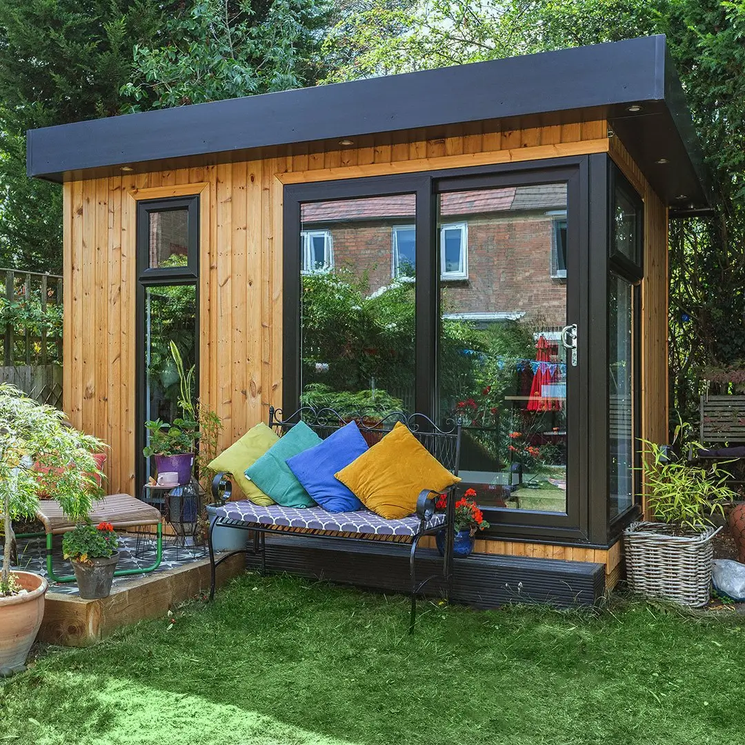 Cabin Master Cedar Office with bench in front and colourful cushions on top of it in grassy lawn area