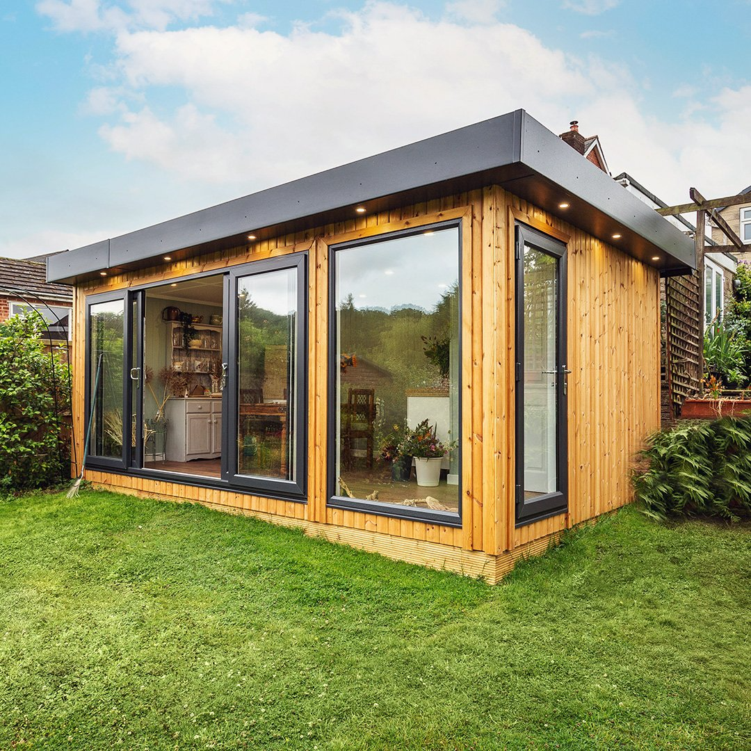 Redwood Garden Room with large glass sliding doors open in grassy lawn area with hedges either side