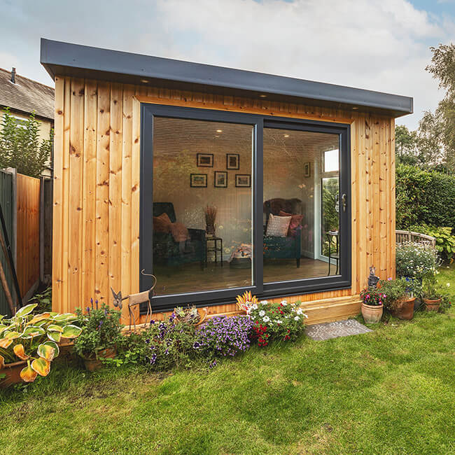 Small insulated timber outdoor building with black sliding doors