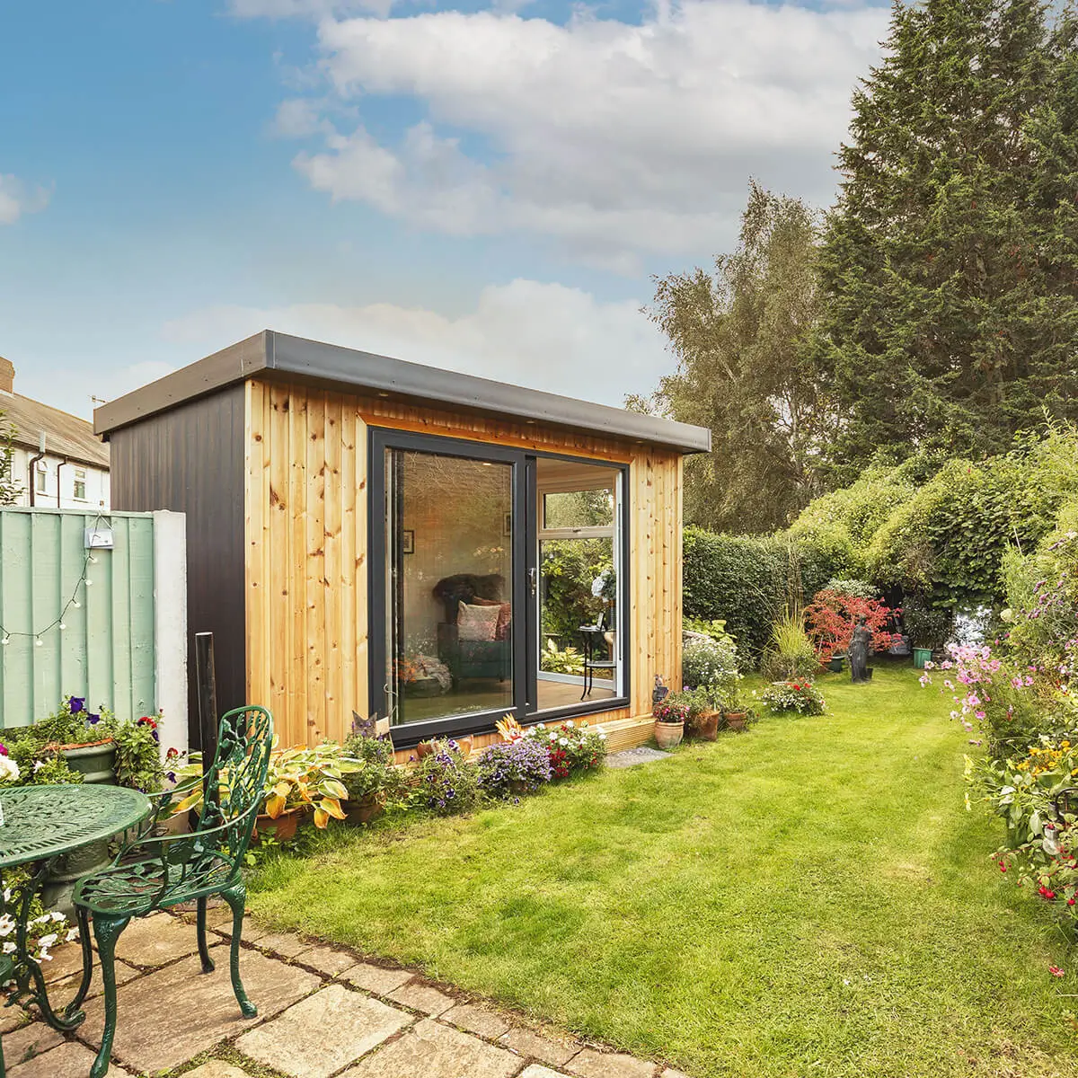 small garden summerhouse timber building with lawn area and patio with table and chairs 