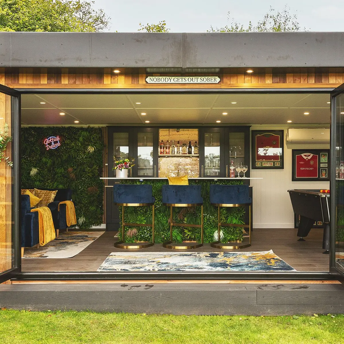Garden Room with Bar and large open bifold doors with view of velvet blue bar stools