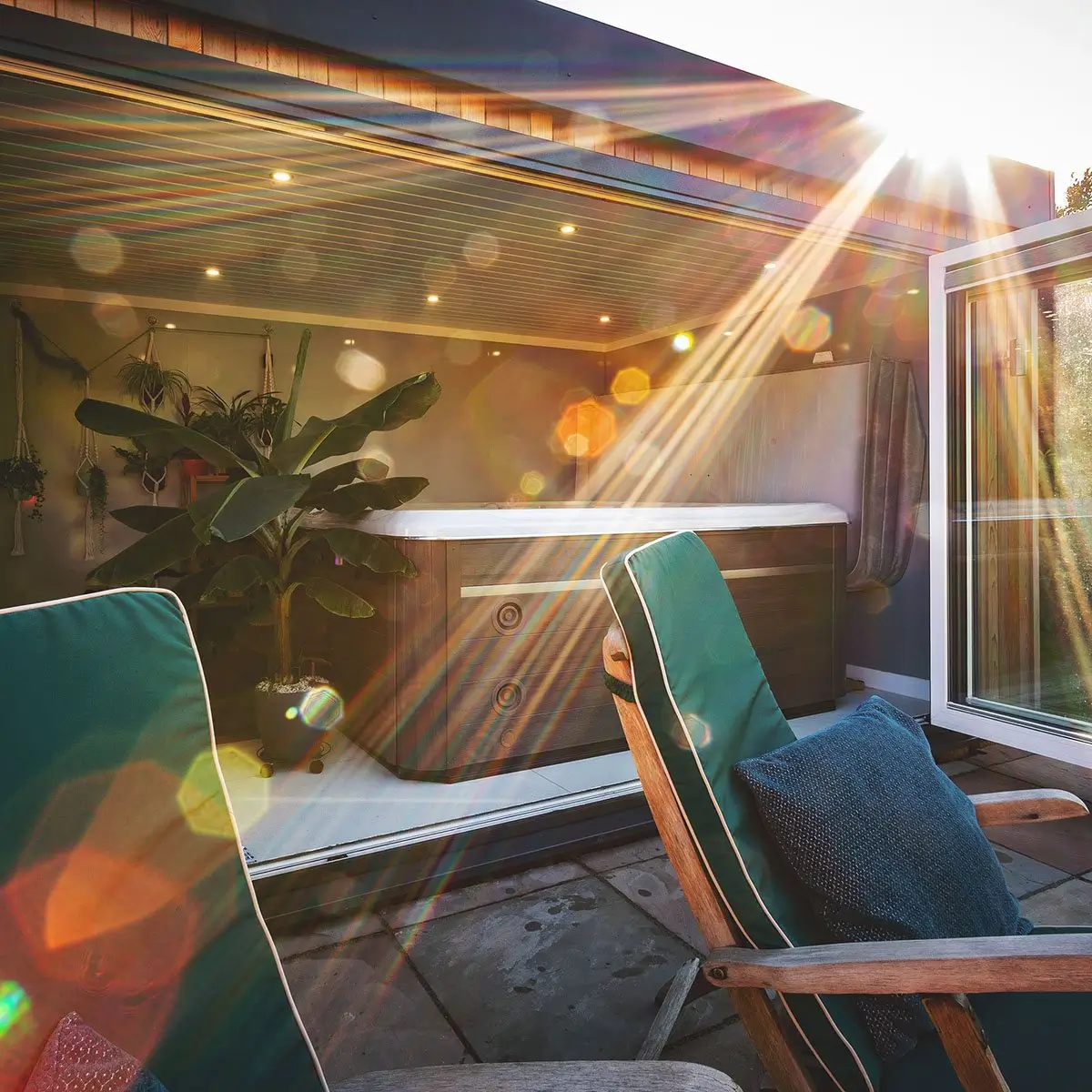 large garden room with deck chairs in front of it on a patio area with open bifold doors and hydropool midlands hot tub