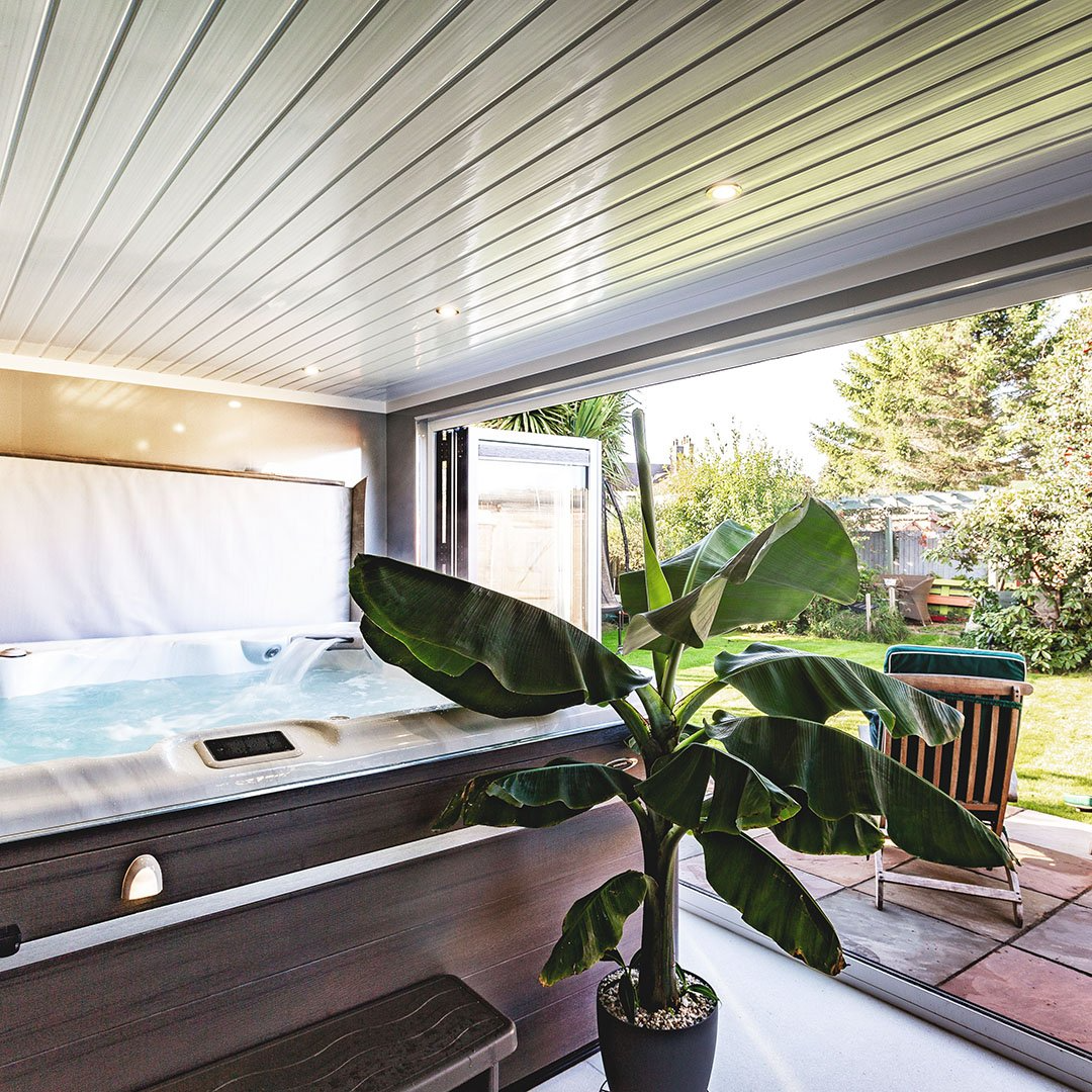 Large Hot Tub Room with cheese plant in a pot and bifold doors open onto lawn area