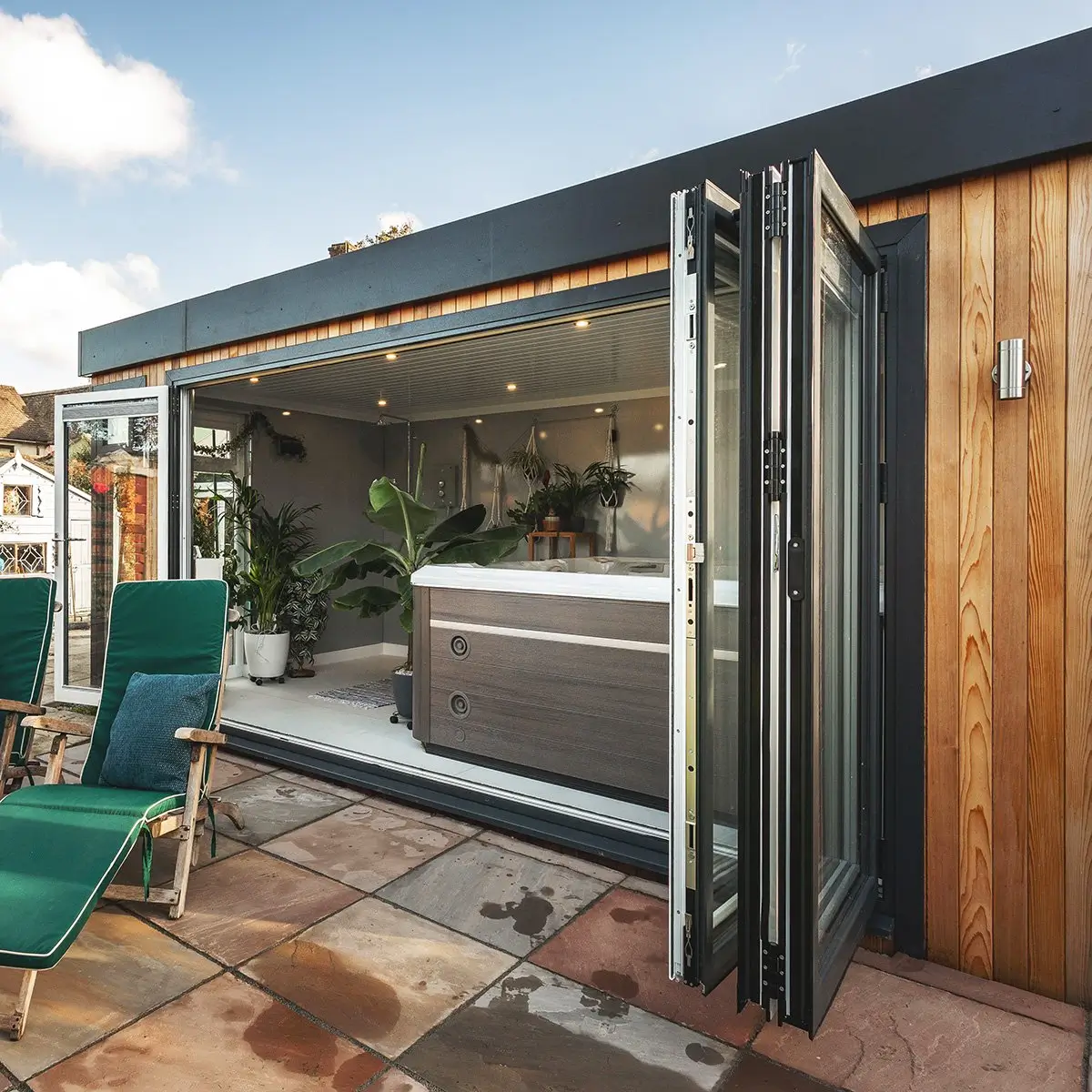 Cedar Garden Room with bifold doors with patio area and hot tub and indoor plants and green sun loungers