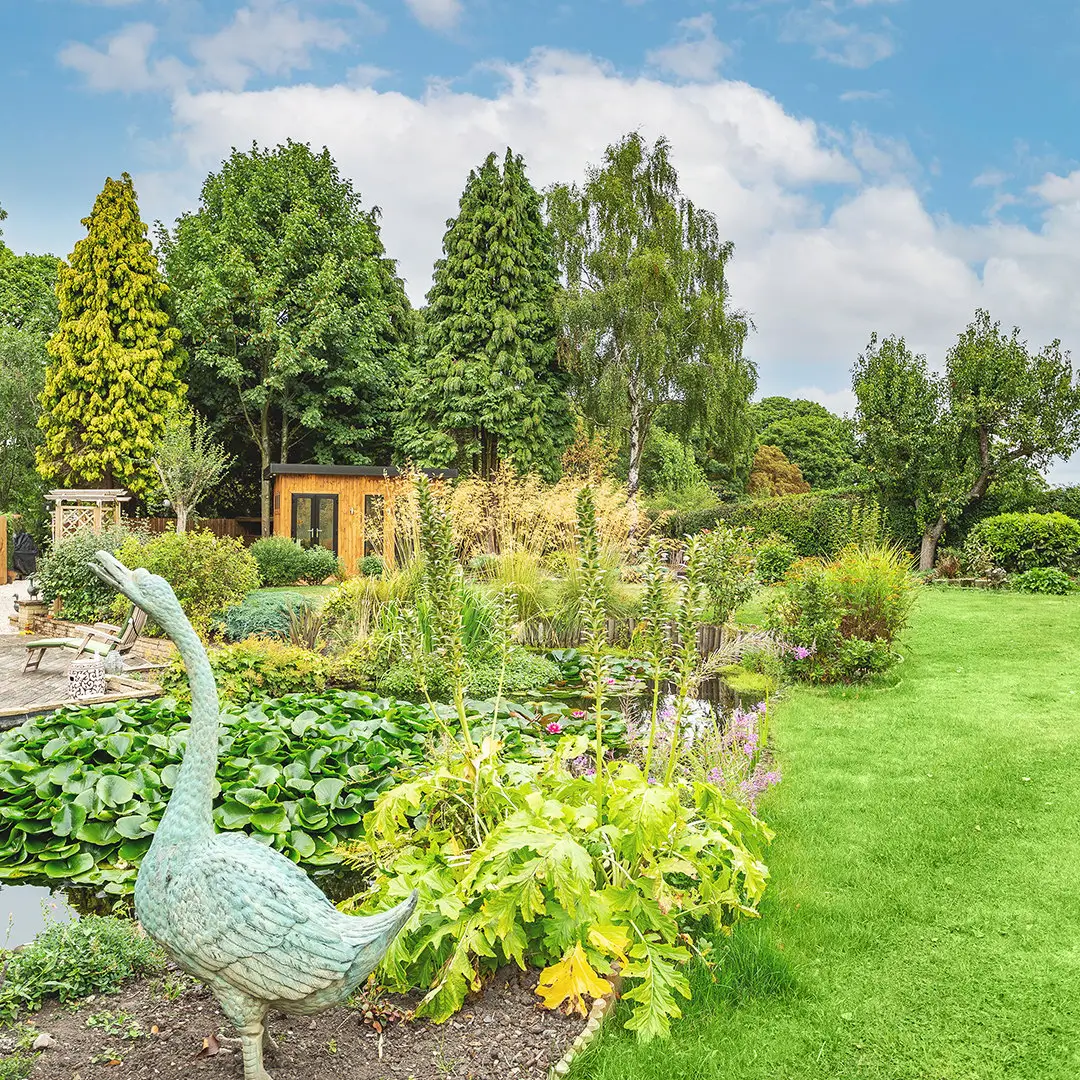 Cabin Master Redwood Garden Room in large grassy lawn area with foliage surrounding it