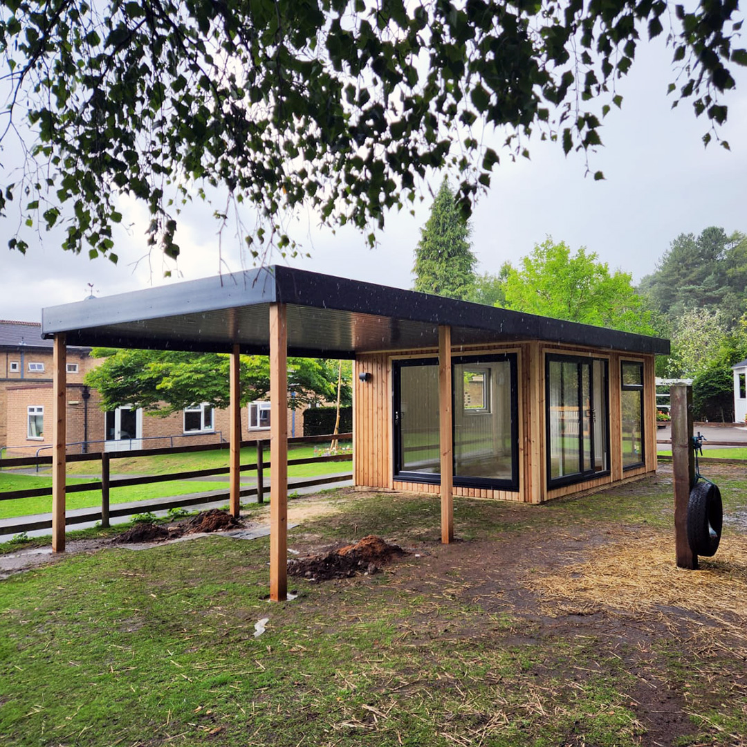 Large cedar garden building with veranda in large grassy field 