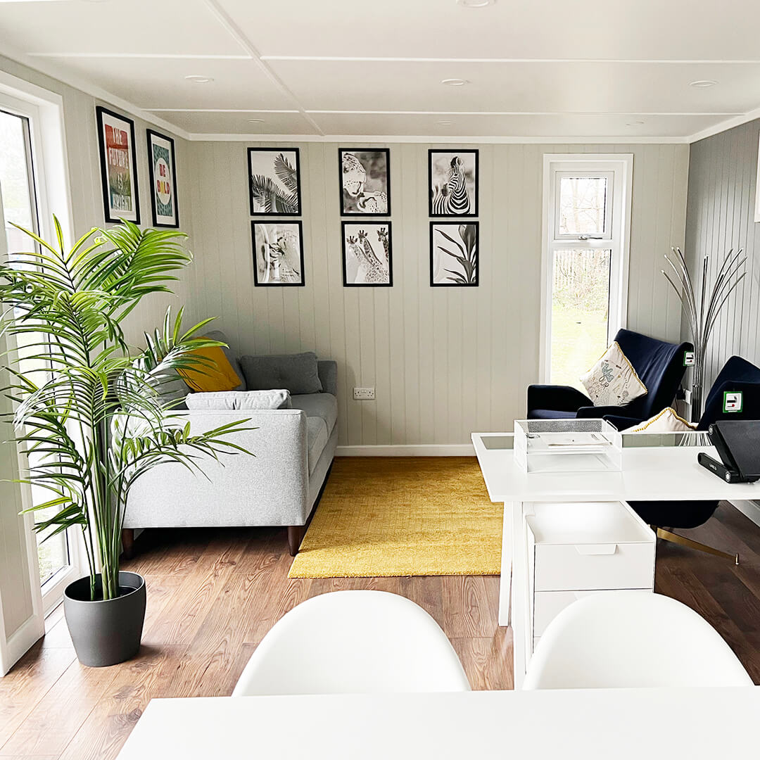 Interior of a bespoke school room cabin with plants, desks and pictures on wall