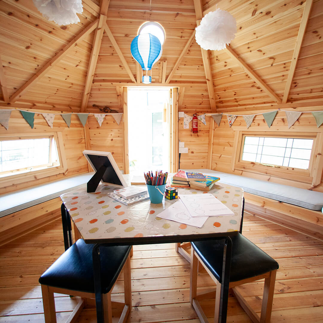 Interior of a timber school cabin with hanging decorations an seating