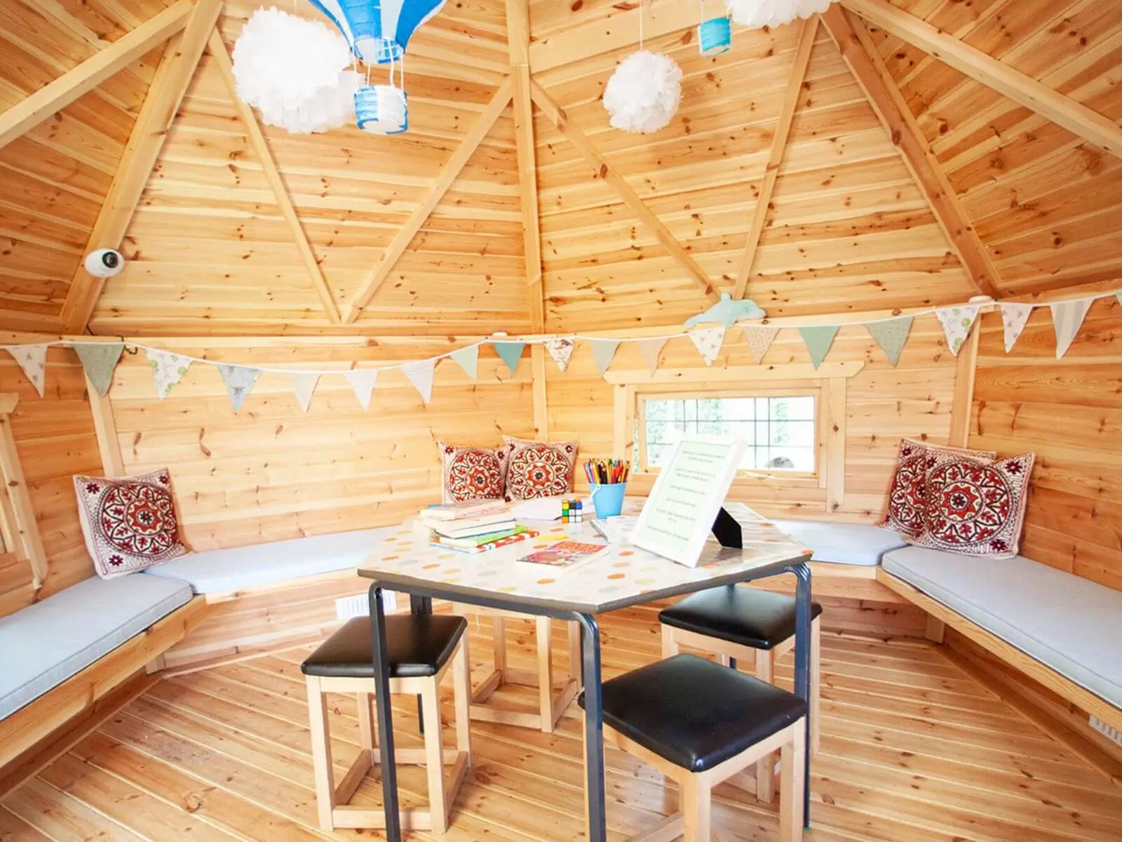 Cabins For Schools George Spencer inside view with benches and chairs and table with bunting and cushions and wall hangings