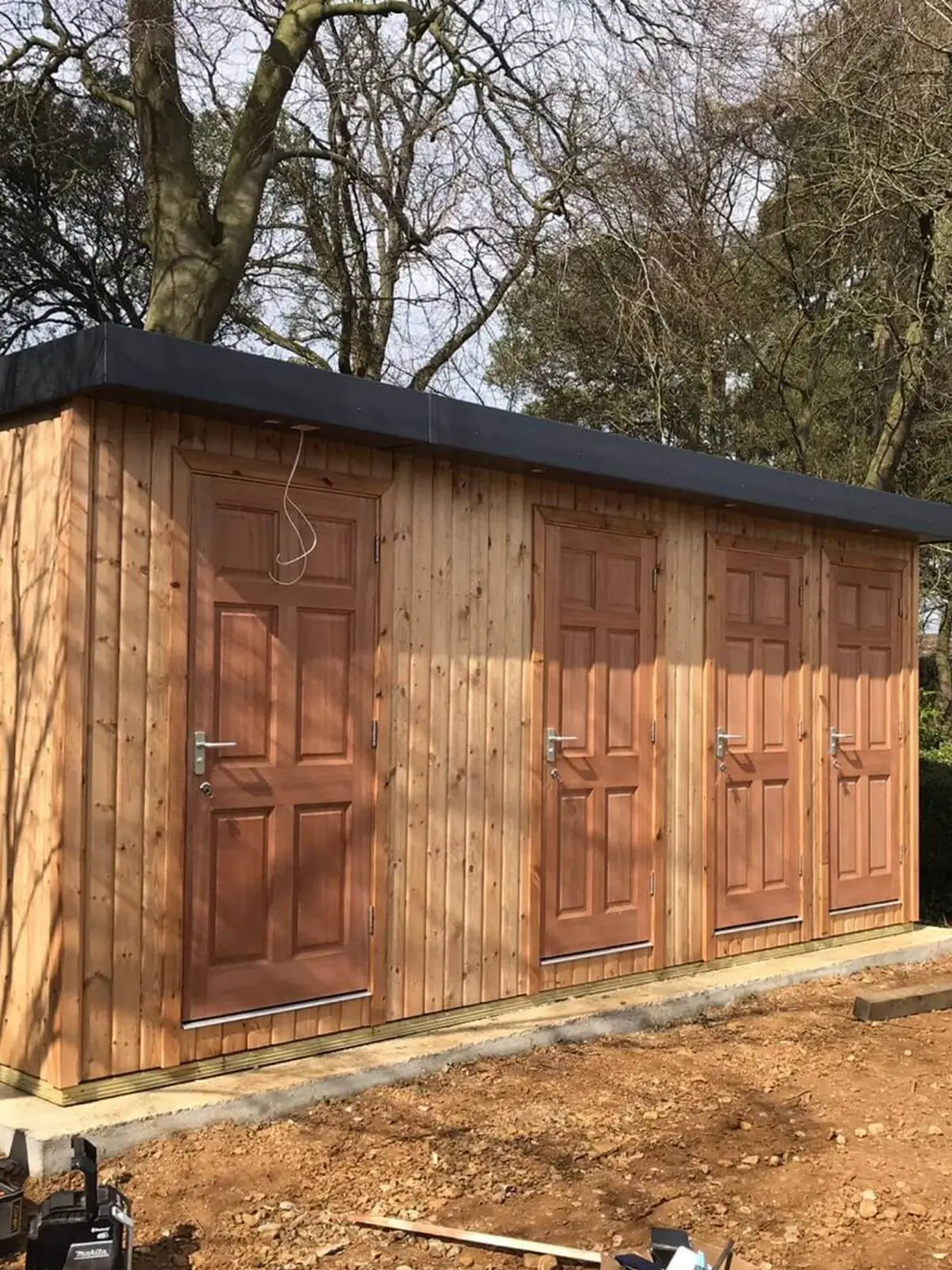 camping cabins toilet block with trees in background and builders tools in foreground 