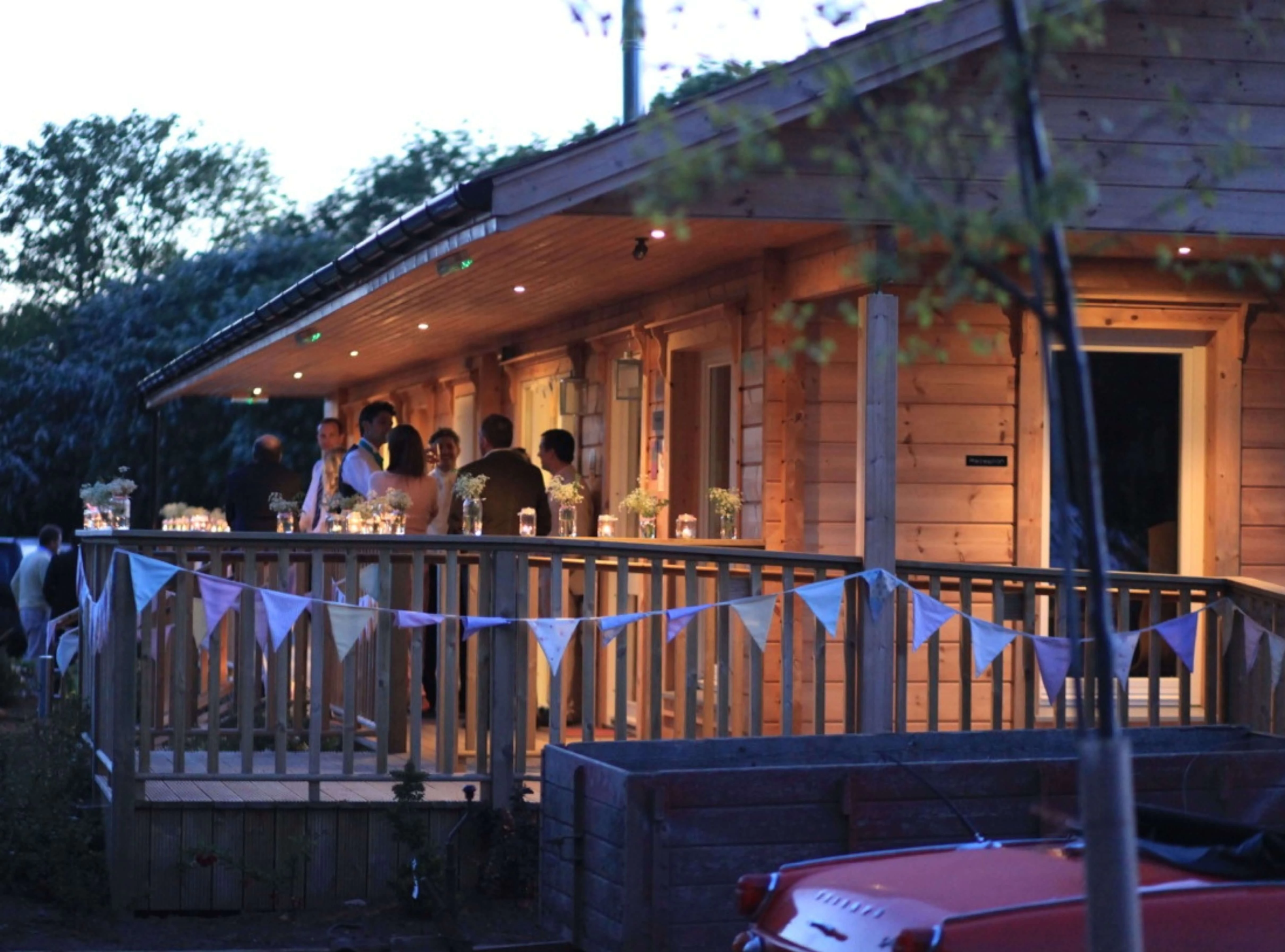 facilities building wedding function room camping cabins with bunting and group of people and spotlights 