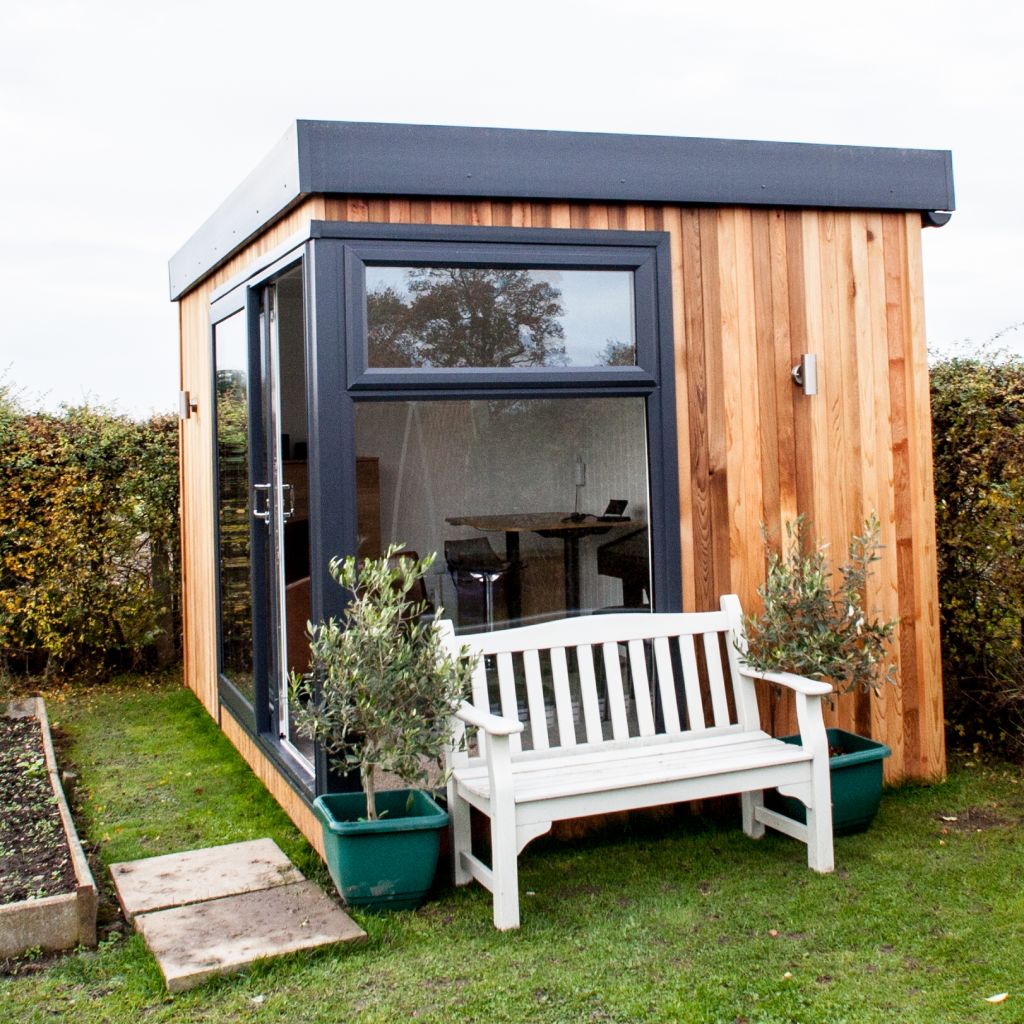 External image of Cabin Master Garden Room with bench in front surrounded by grassy lawn area with potted plant