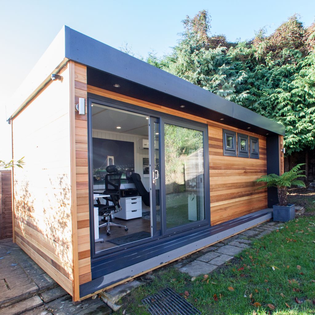 External view of Cabin Master Garden Music Room with view into desk chair and studio equipment and large green lawn area