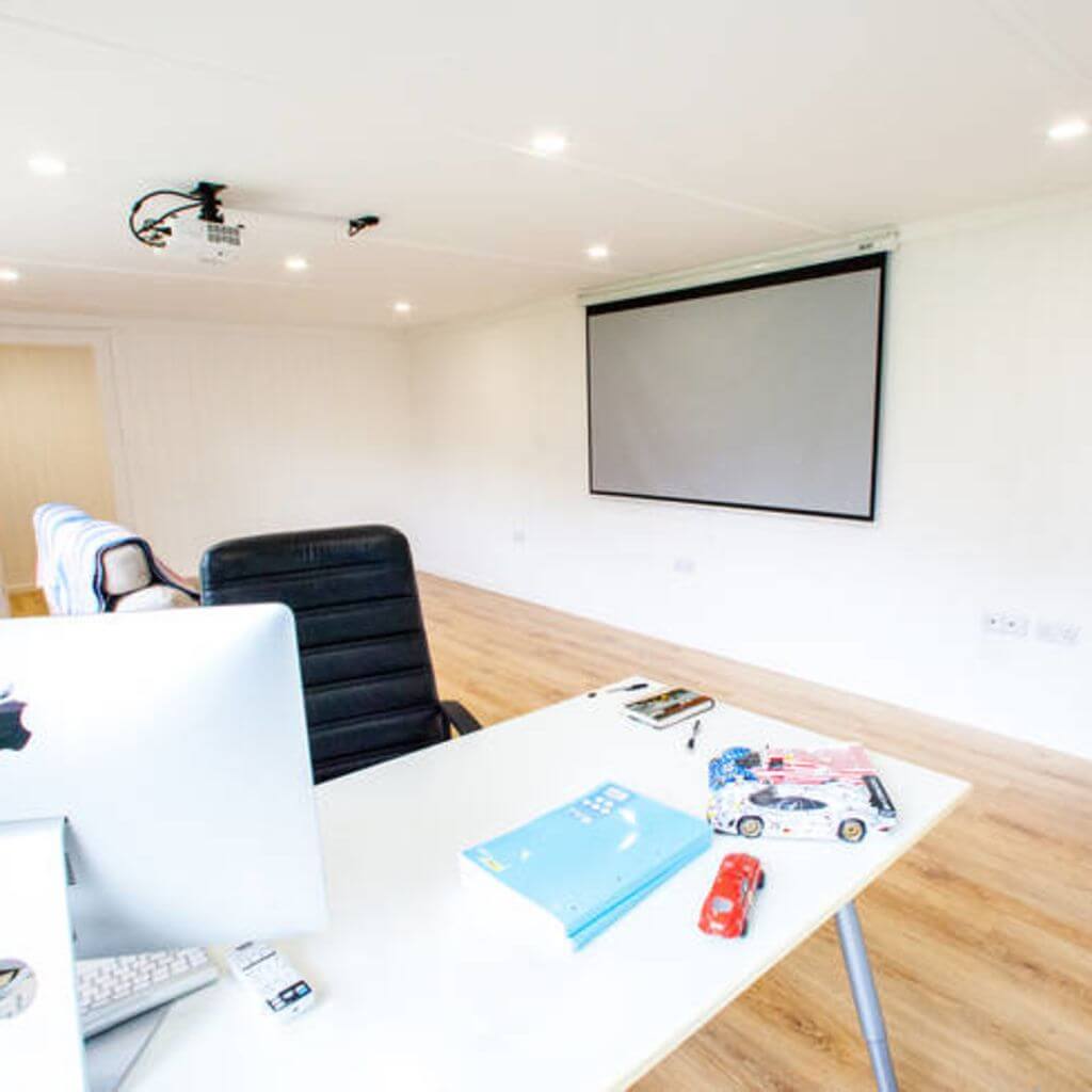 Projector on wall with desk chair and apple mac cmputer inside cabin master garden cinema room
