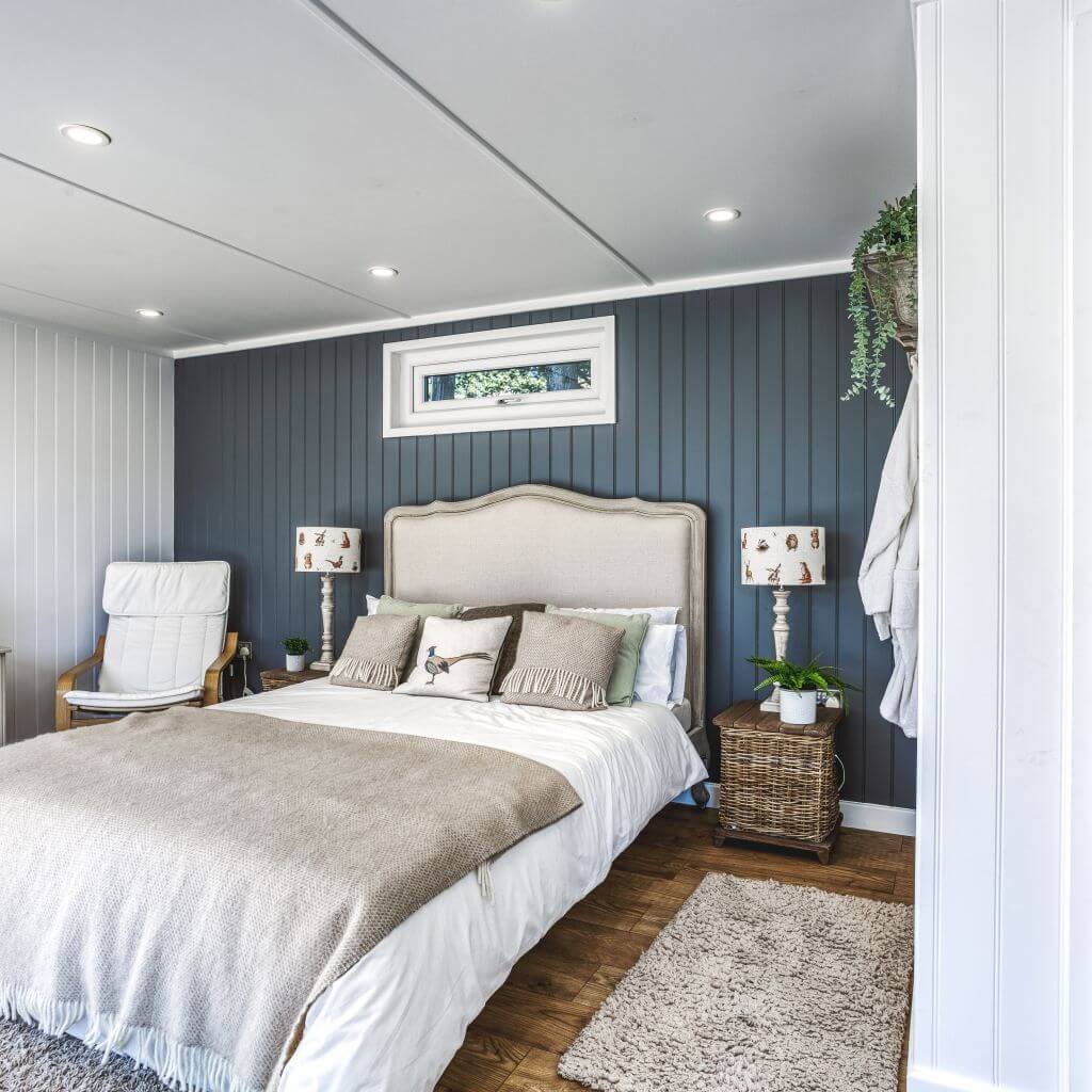 inside view of show site lodge annexe and rattan side tables with lampshades and grey feature wall and leather armchair
