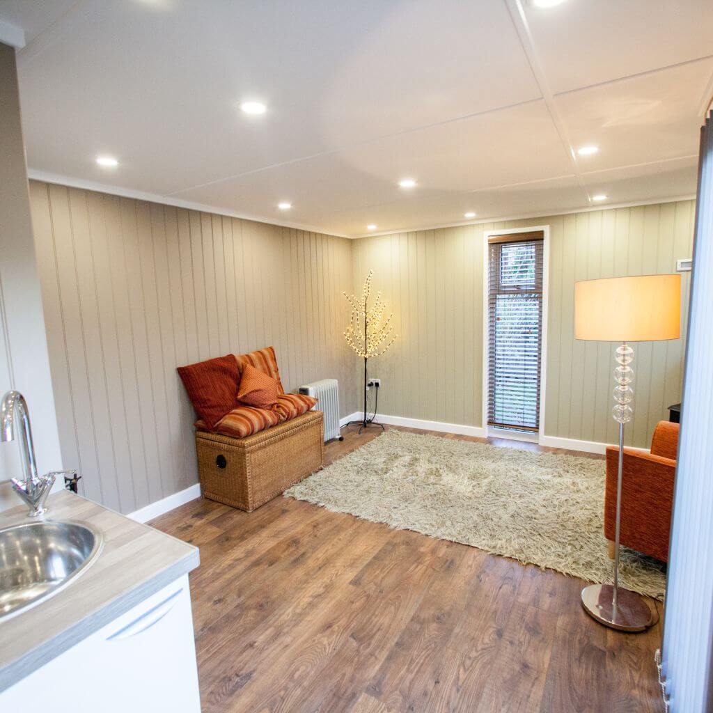 inside view of redwood massage room with beige rug and orange cushions, home furnishings and sink
