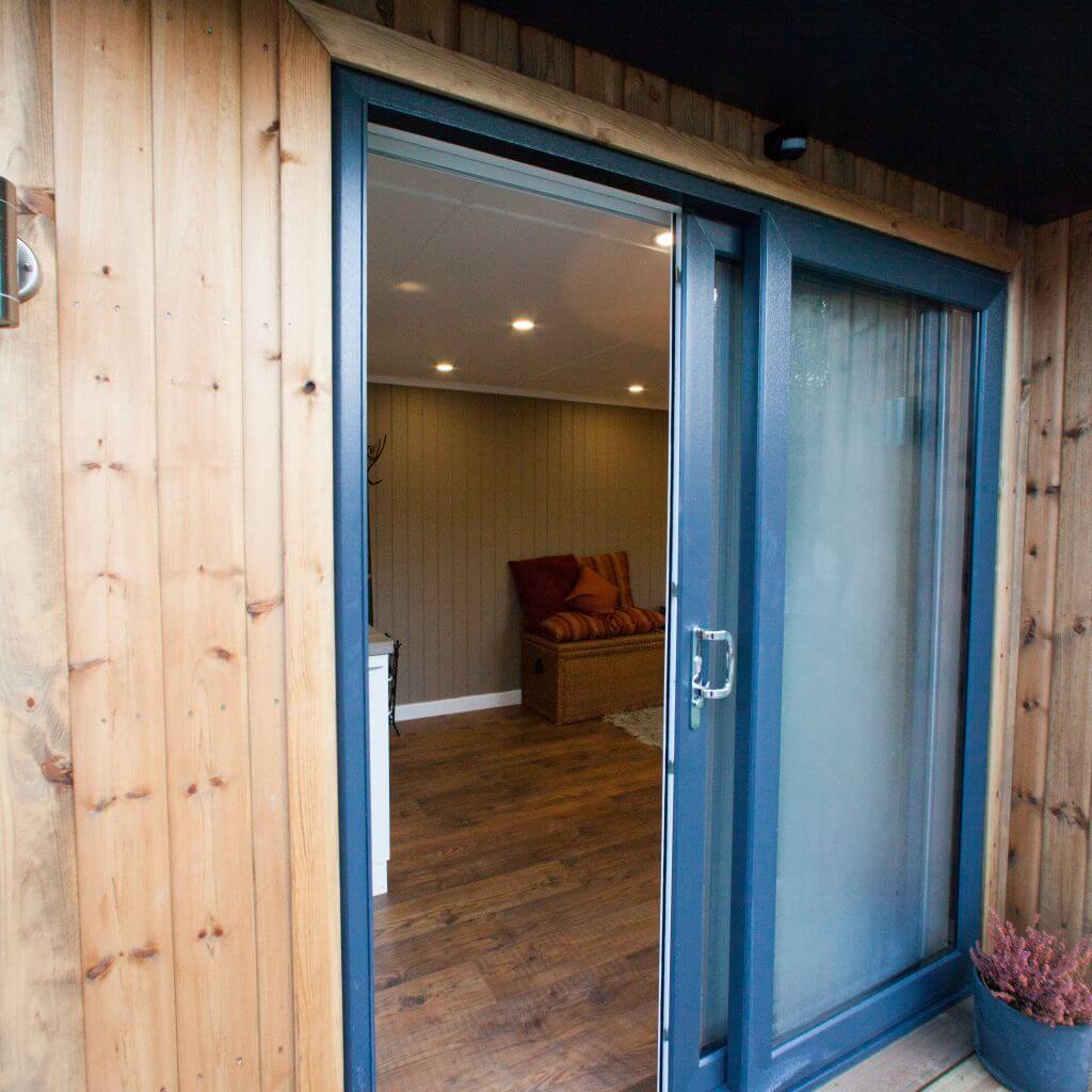 redwood garden massage room with open door and view into building with orange cushions