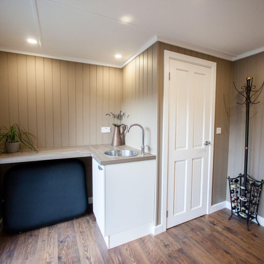 inside view of garden massage redwood room with partition door and in built sink unit