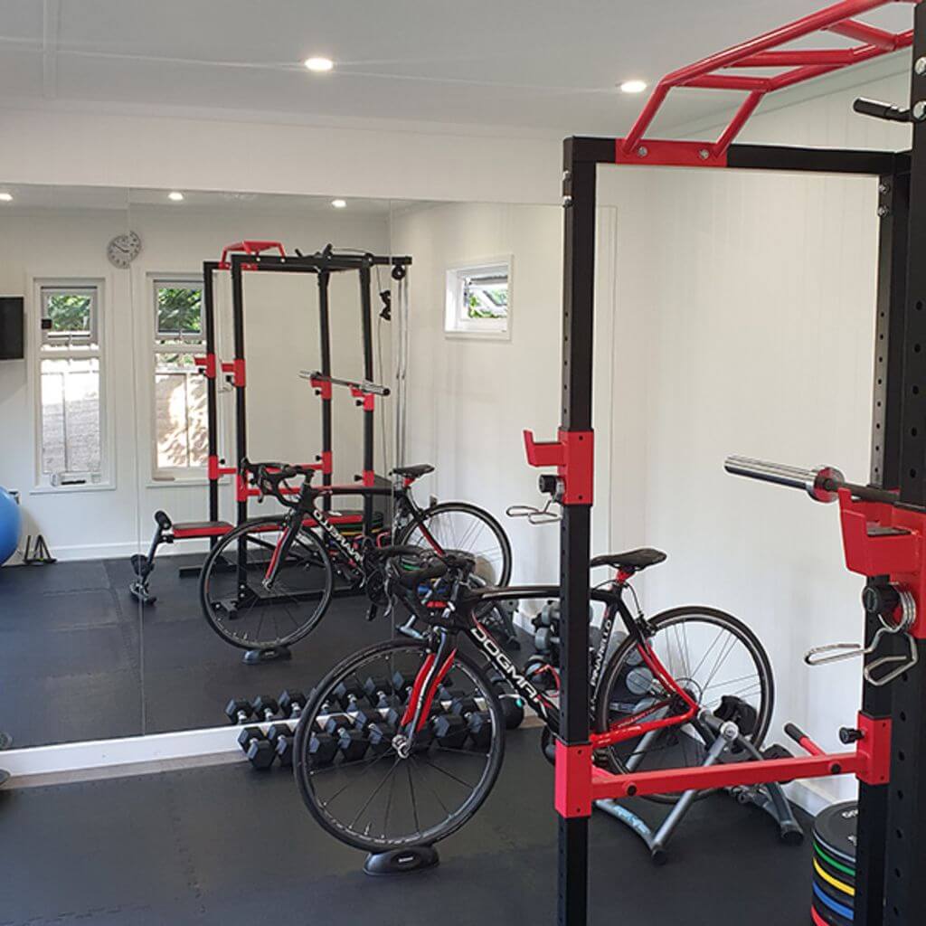 Inside Garden Gym with Squat Rack Bench Press and Large Mat Area with Dumbbells and Bike