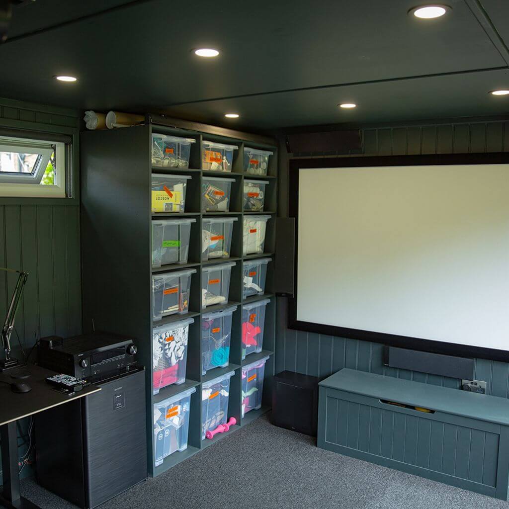 inside of garden cinema room with a large projector screen and a desk