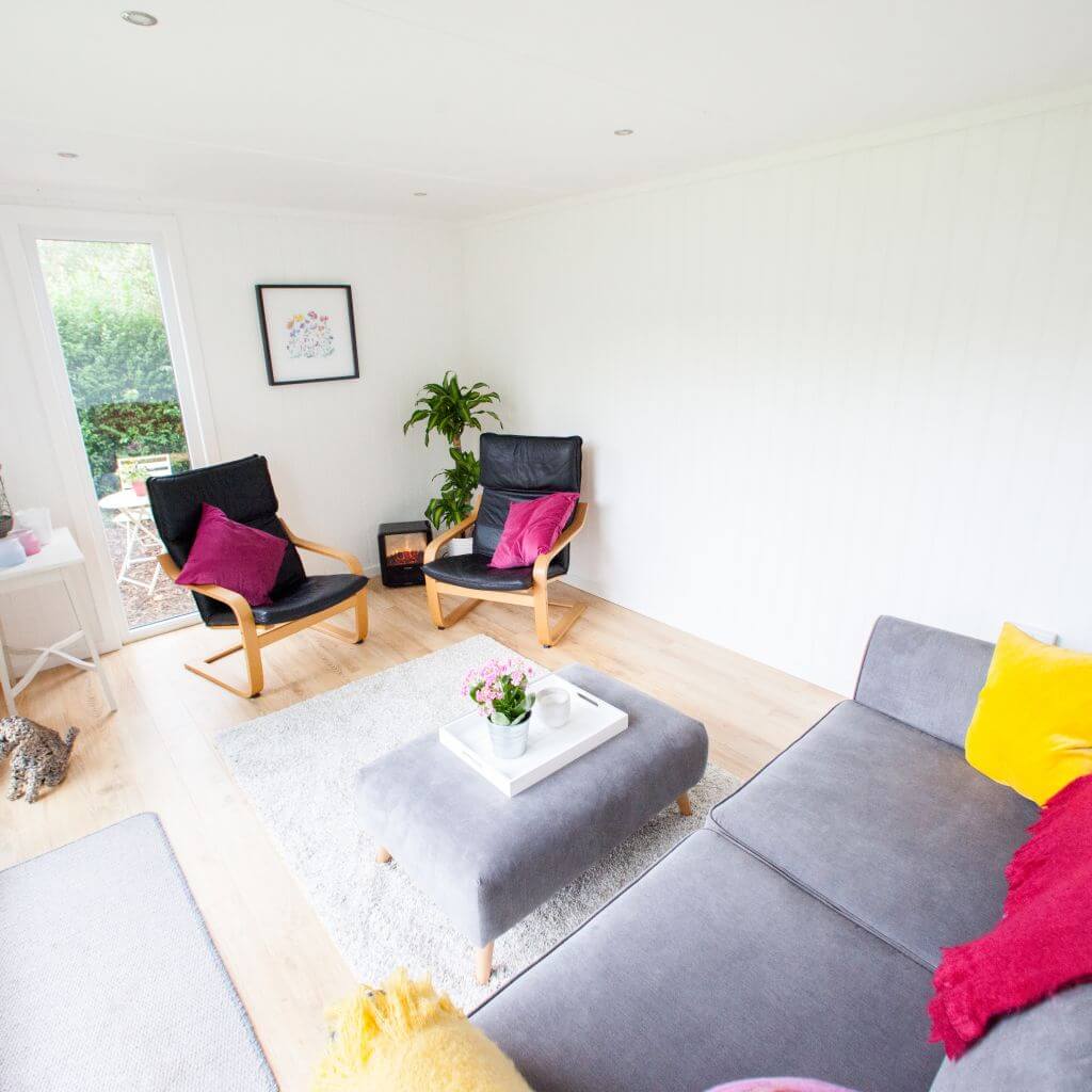 inside garden pod timber building with black leather chairs and grey couch with home furnishings