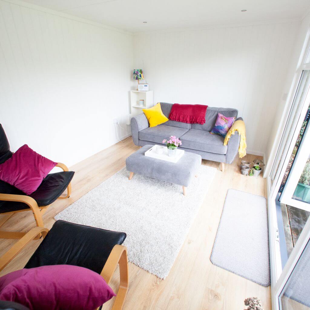 inside small garden pod with grey couch and leather chairs with open doors