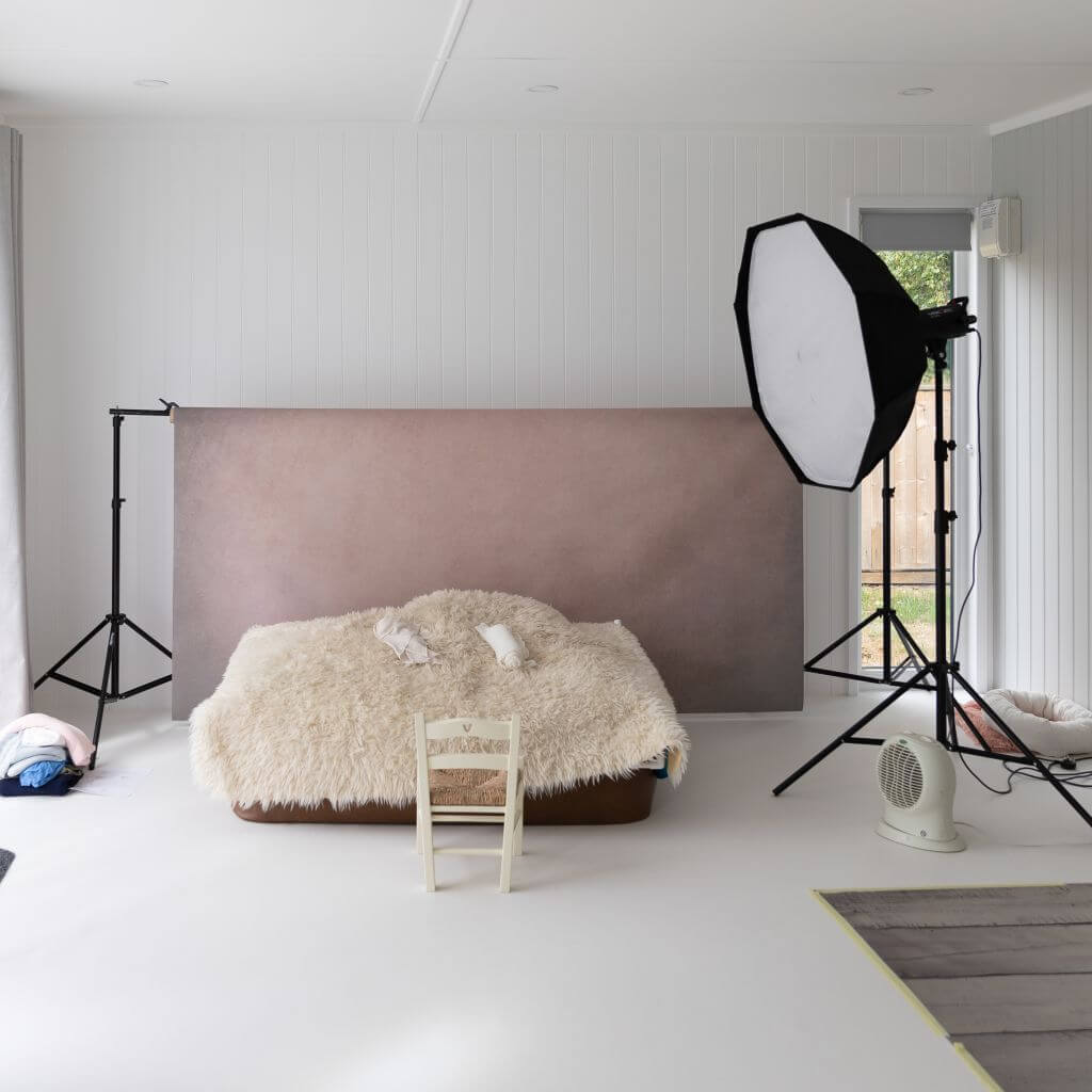 large photography studio with soft box and bed and props with large white walls and flooring   