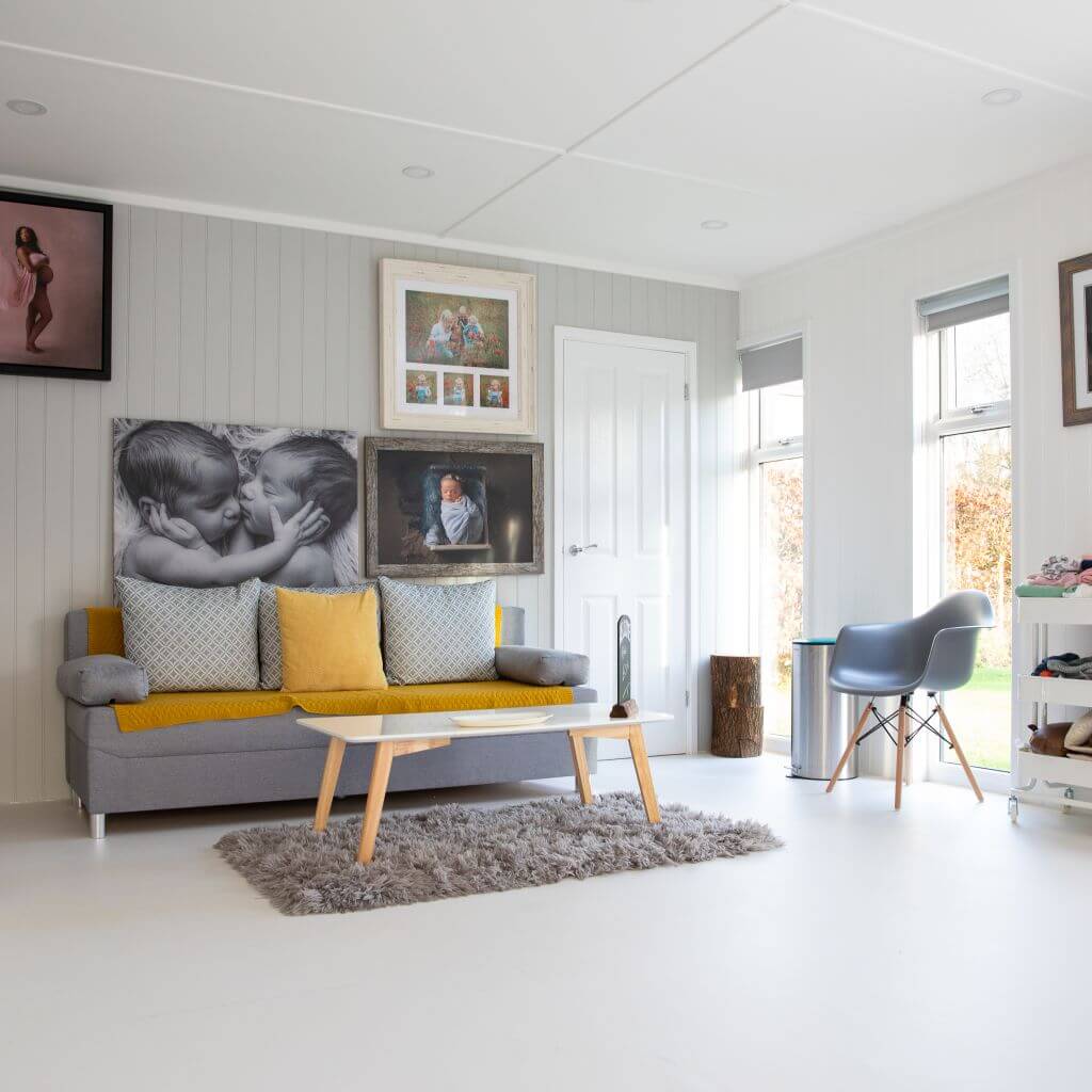 photography studio with large white flooring and white walls with grey couch and furniture 