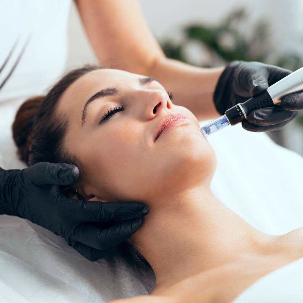 woman laying on massage bed getting a laser facial in garden studio beauty room