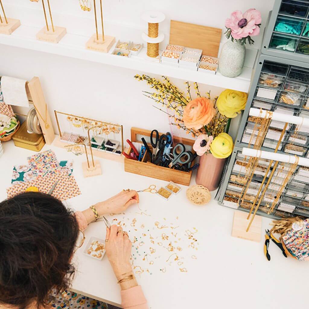 woman cutting fabric in hobby and craft room with assortment of materials and scissors 
