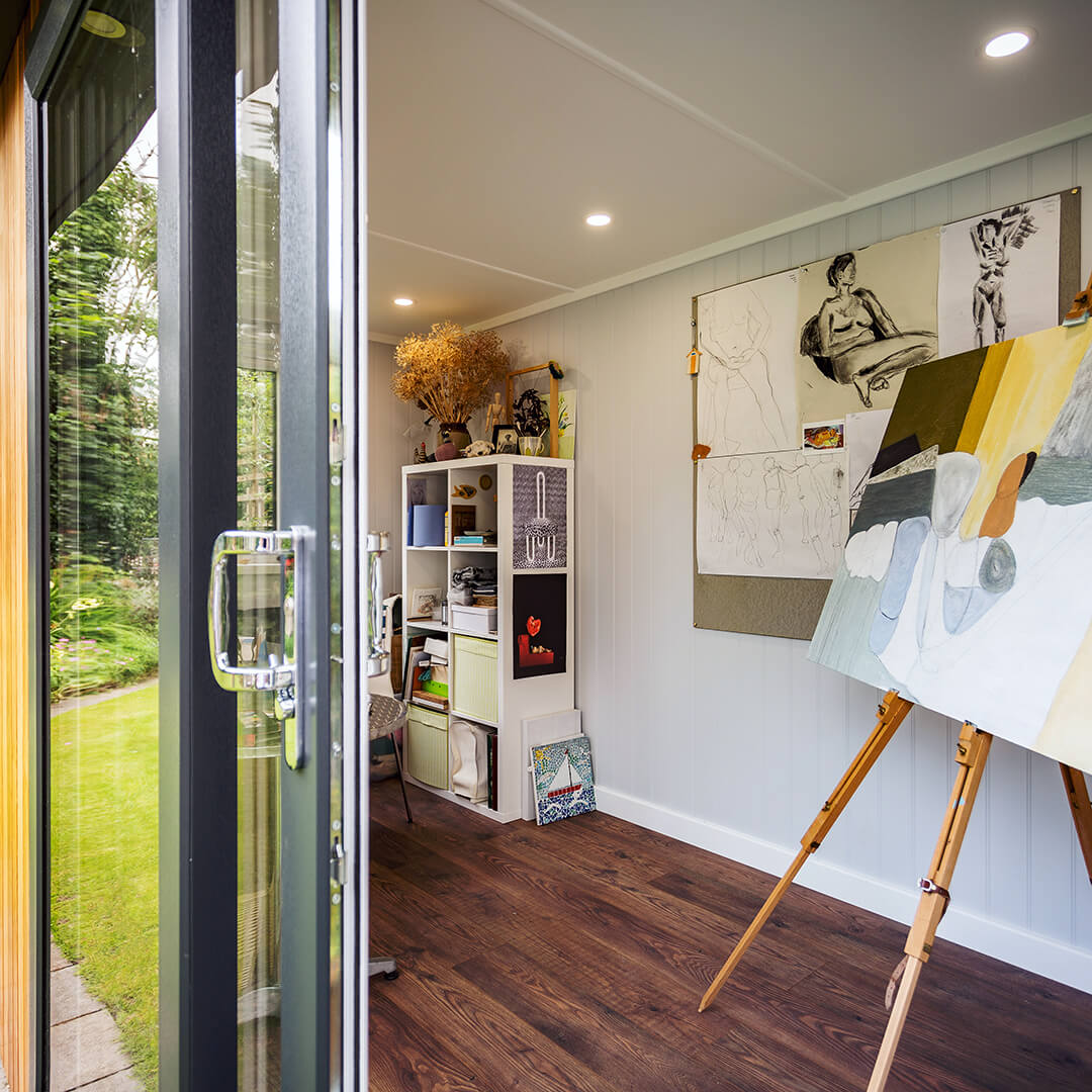 sliding glass doors open into hobby and craft room with large easel and cabinet with art supplies 