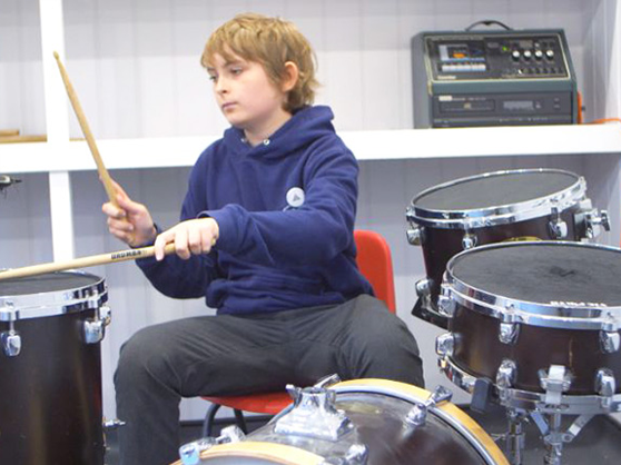 Pupil at Langar Primary School playing the drums on their new cabin