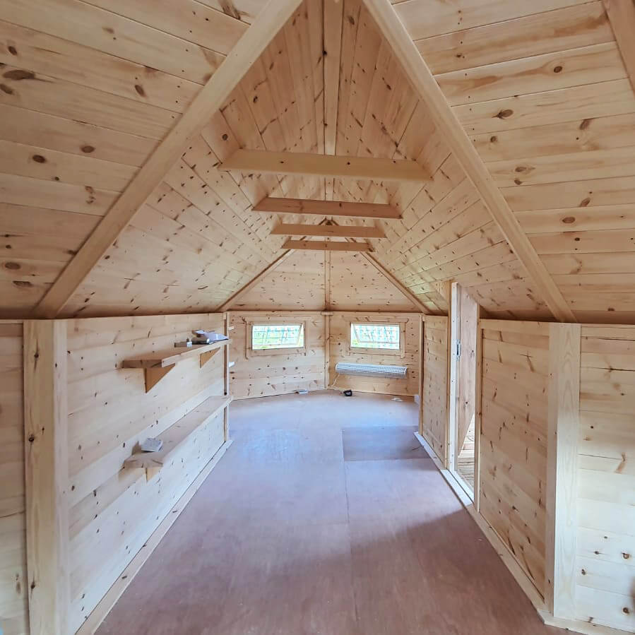 Inside a large scandi school hut, with exposed timber throughout