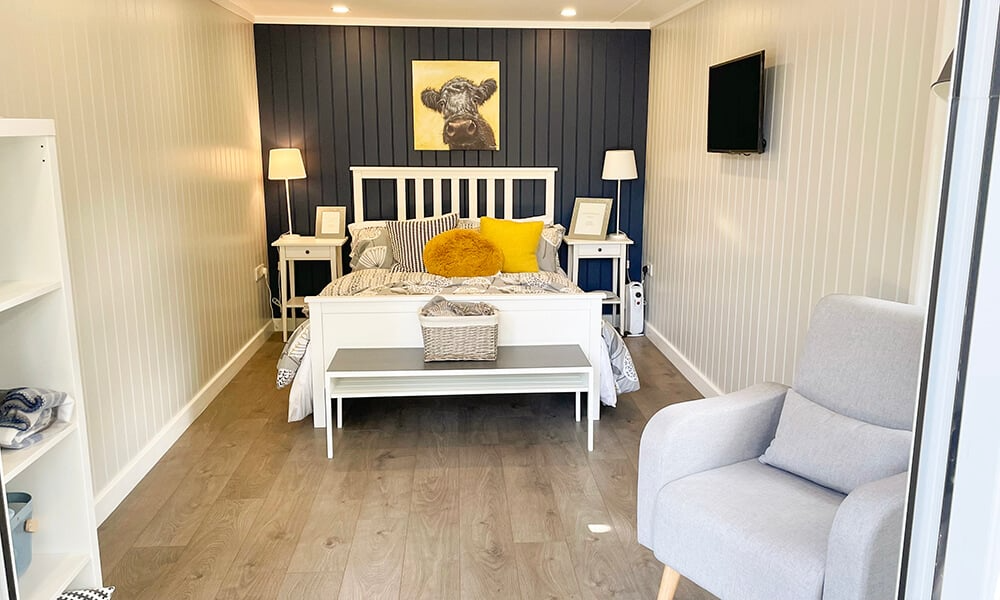 Interior of a spare room in the garden with navy blue feature wall, bed and yellow accents