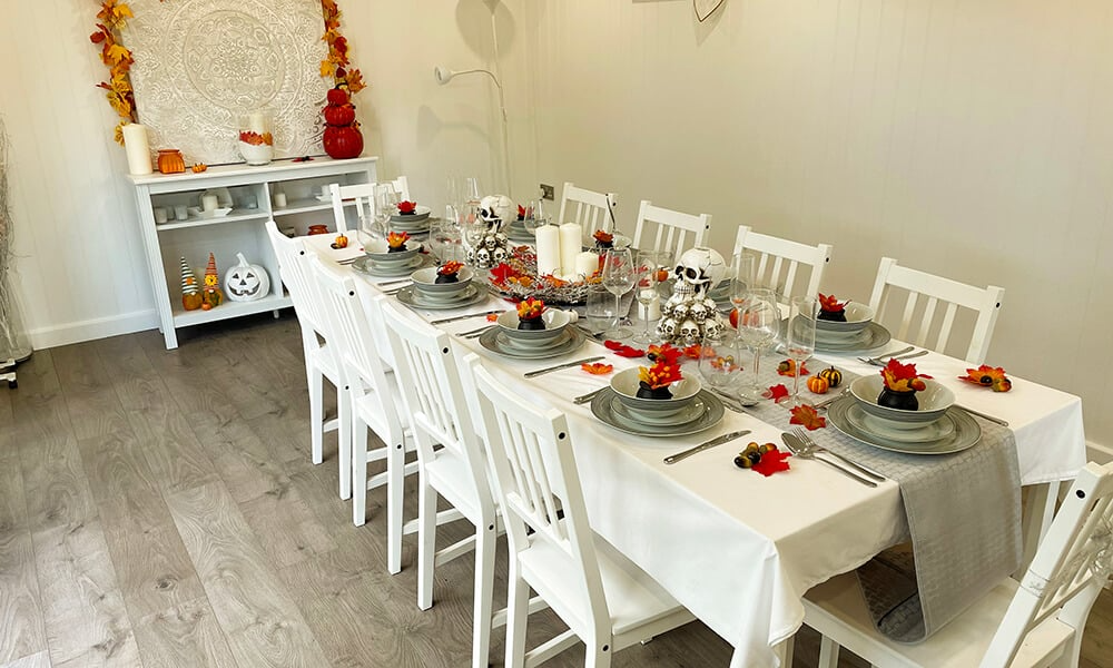 Interior of a garden dining room set up for Halloween with large dining table and autumnal accessories