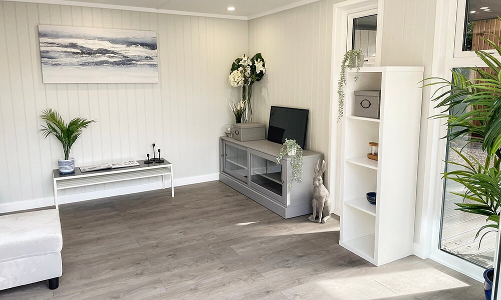 Interior of a garden room snug with grey wood floor, white walls and grey & navy decor