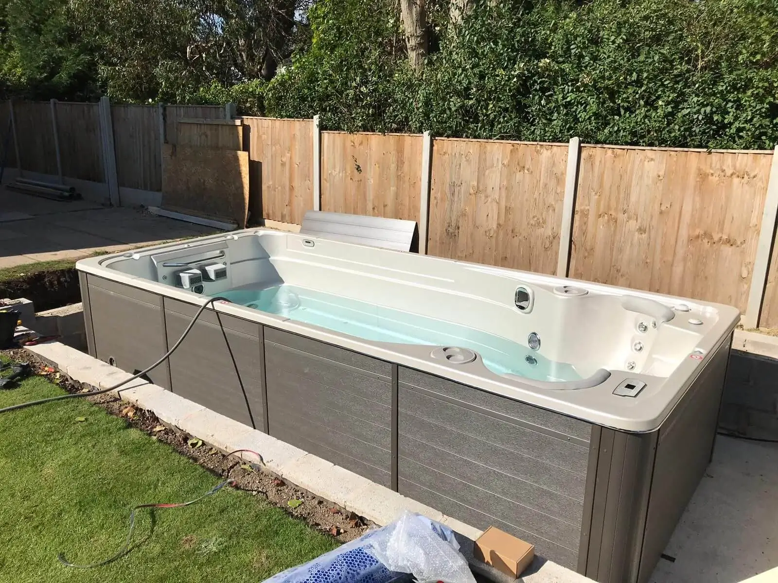 hydropool midlands swim spa in garden with grassy area and patio and fencing behind