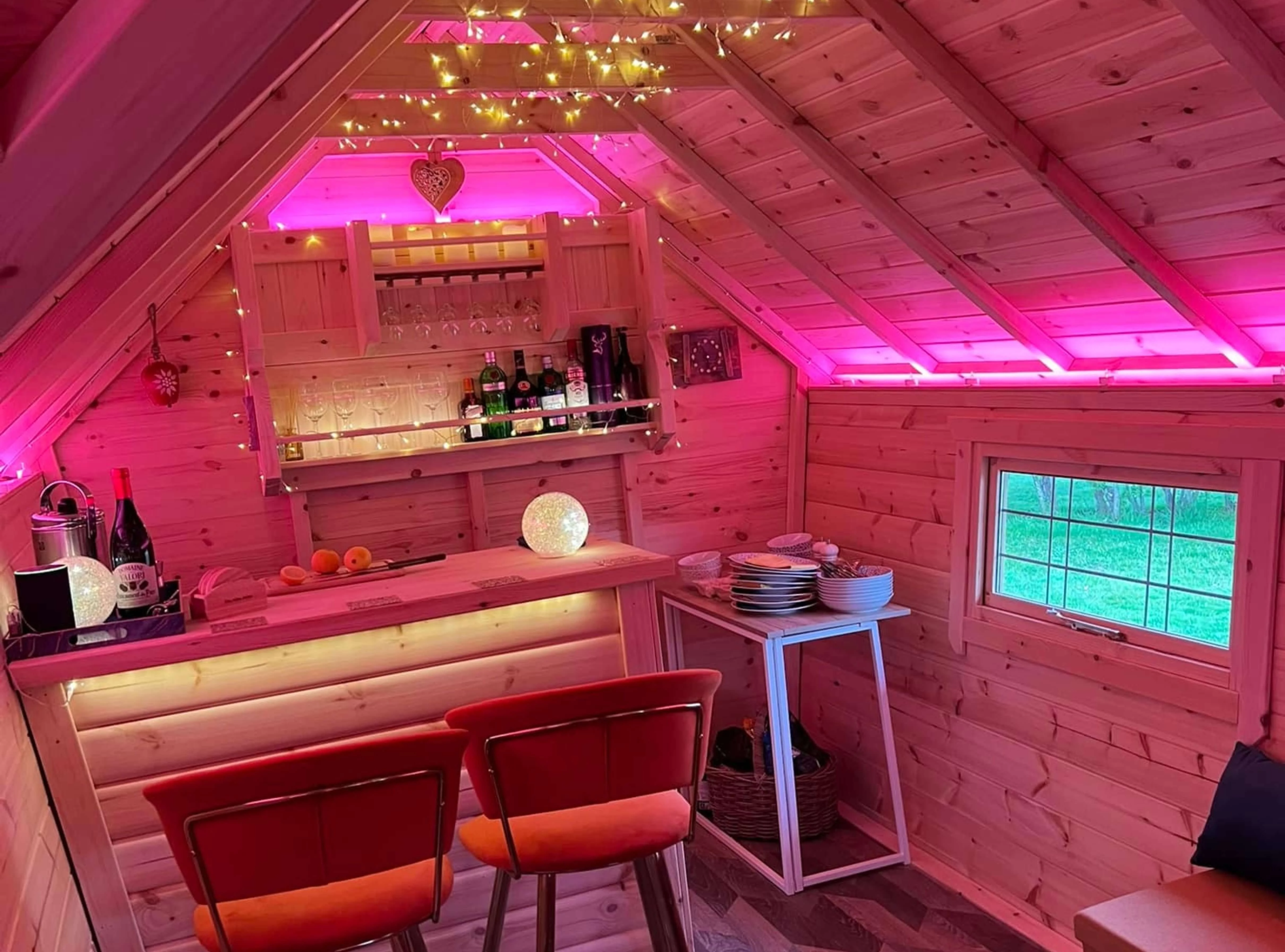 Arctic Bar with red stools and fairy lights and pink LED lights and gin bottles and white ceramic plates 